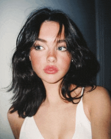 a close up of a woman 's face with a white tank top on