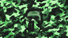 a man wearing a gas mask is surrounded by a green camouflage pattern