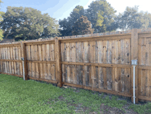 a wooden fence surrounds a lush green field with trees in the background