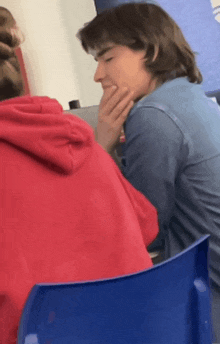 a man in a blue shirt sits next to a woman in a red sweatshirt