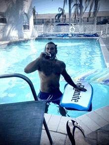 a man in a swimming pool with a board that says " dynamite " on it