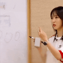 a woman is pointing at a white board with a marker .