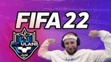 a man wearing headphones and a headband is flexing his muscles in front of a sign that says fifa 22 .