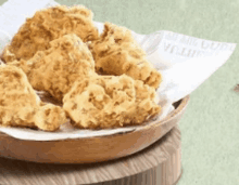 a wooden bowl filled with fried chicken on a piece of paper that says ' chicken ' on it