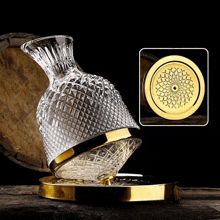 a glass decanter with a gold rim sits on a wooden table next to a wooden barrel