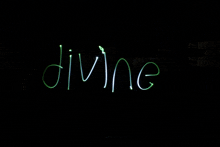 the word divine is written in green light