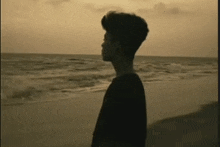 a man standing on a beach looking at the ocean .