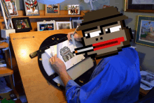 a man is drawing on a piece of paper with a pixelated monkey behind him