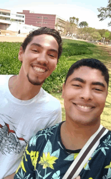 two men are posing for a picture and one is wearing a shirt that has flowers on it