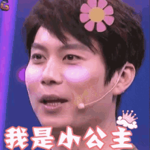 a man wearing a microphone and a flower on his head with chinese writing behind him