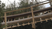 a wooden railing with a chain link fence behind it