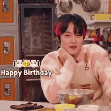 a young man in a pink and white sweater is sitting at a table with a bowl of food and a sign that says happy birthday