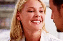 a woman in a lab coat is smiling at a man .