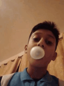 a young boy is blowing a bubble of chewing gum in front of his face .