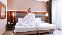 a woman is laying on a bed with a white comforter