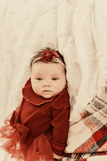 a baby girl wearing a red dress and headband