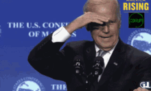 a man in a suit and tie is standing in front of a microphone with the u.s. conference of minds behind him