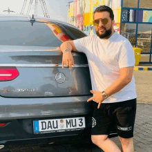 a man stands in front of a mercedes with a license plate that says dau mu 3