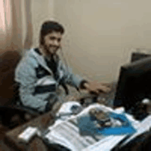 a man is sitting at a desk in front of a computer and wearing headphones .