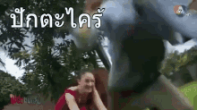 a woman in a red dress is sitting in front of a statue in a park with a foreign language .