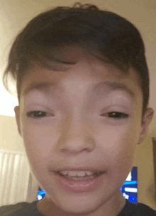 a close up of a young boy 's face with a tv behind him