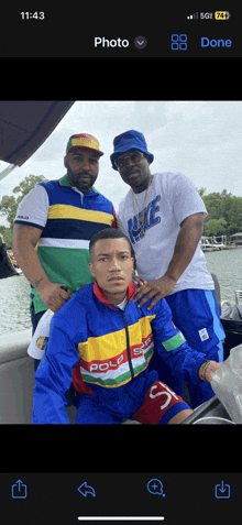 three men are posing for a picture and one of them is wearing a polo jacket