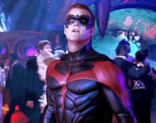 a man in a superhero costume is standing in a crowded room .