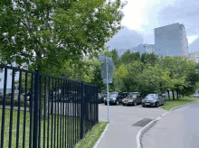 a row of cars are parked on the side of the road in front of a fence