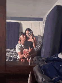 a man and a woman are taking a selfie in a bedroom