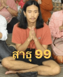 a man in a red shirt sits in a lotus position with the number 99 above him