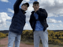 two young men are standing next to each other in a field and one of them is wearing a shirt that says adidas