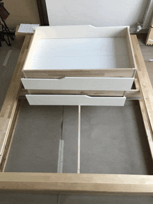 a wooden bed frame with two white drawers underneath