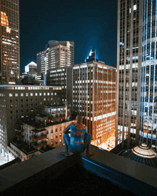 a person in a spiderman costume sits on a ledge overlooking a city