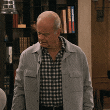 a man in a plaid shirt is standing in front of a bookshelf that has a book titled " making a fortune "