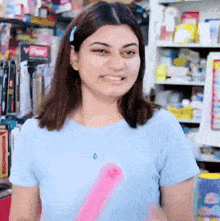 a woman in a blue shirt is smiling in front of a shelf with a sign that says ' power ' on it