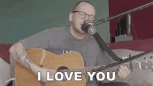 a man singing into a microphone while holding a guitar with the words " i love you " above him