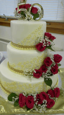 a white and gold cake with red roses and the number 50 on top