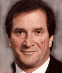 a close up of a man 's face wearing a suit and tie and smiling .