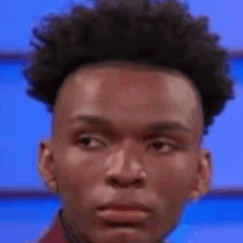 a young man with curly hair is making a funny face while looking at the camera .