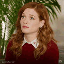 a woman with red hair is wearing a red sweater and white collar