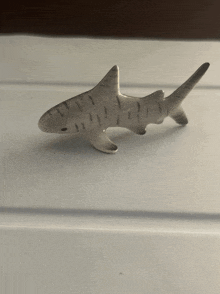 a small shark figurine is on a white surface