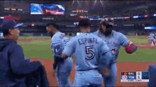 a group of baseball players are standing on a field and one of them has the number 5 on his back .