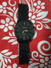 a premier quartz watch is laying on a red and white floral cloth