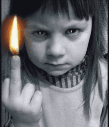 a little girl is giving the middle finger with a lit match in her hand .