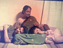 a group of people laying on a bed including a woman and two children