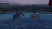 two naked men are sitting in a hot tub