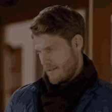 a man with a beard wearing a scarf and a blue jacket