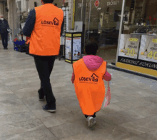 a little girl wearing an orange vest that says losev