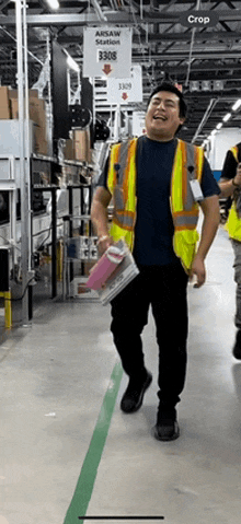 a man in a safety vest is walking in a warehouse with a sign that says areaw station