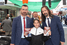 a boy in a nike jacket is holding a book that says ' ekrem demirel ' on the cover